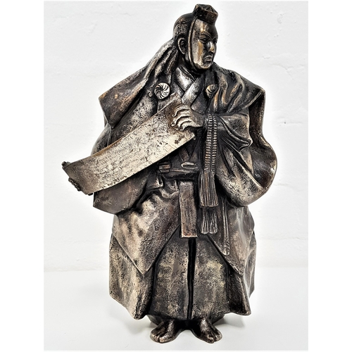 242 - JAPANESE SILVERED BRONZE OF A SHINTO PRIEST
wearing flowing robes and holding a scroll, with charact... 