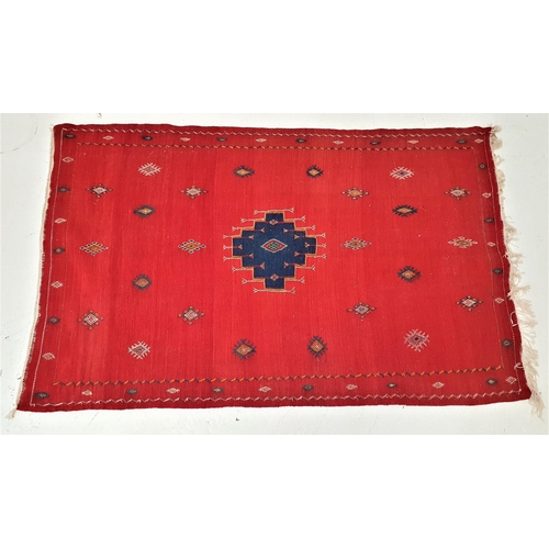 408 - MOROCCAN RUG
with a vivid red ground centered with a blue motif and surrounded by geometric motifs, ... 