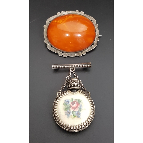 102 - TWO SILVER MOUNTED BROOCHES
one with amber coloured oval cabochon within scroll decorated mount; the... 