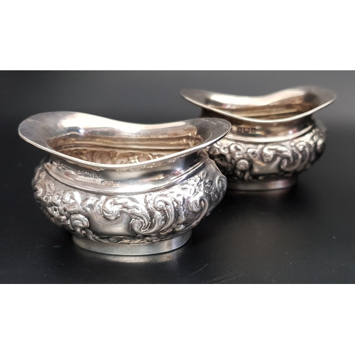 214 - PAIR OF GEORGE V SILVER SALTS
with embossed floral and scroll decoration, Birmingham 1910, 6.8cm wid... 