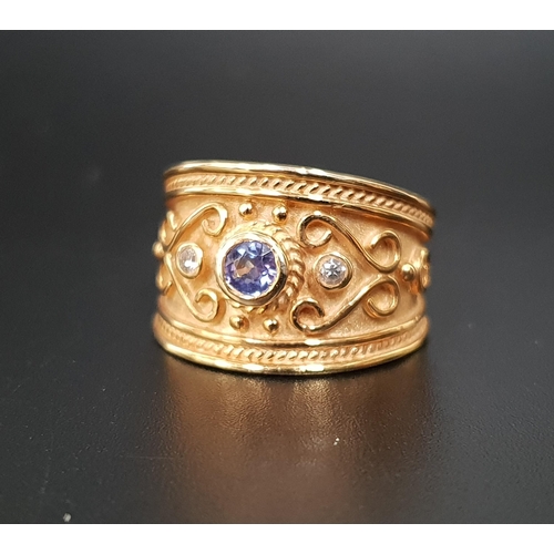 6 - DIAMOND AND BLUE GEM SET RING
the gemstones in wide scroll decorated fourteen carat gold band, ring ... 