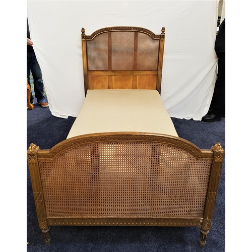 404 - EARLY 20th CENTURY CARVED SINGLE BED
with a shaped gilt rattan head and footboard, standing on turne... 