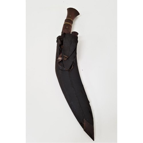 328 - KUKRI KNIFE 
with a 31cm long curved blade with a teak handle with brass fixings, contained in a lea... 