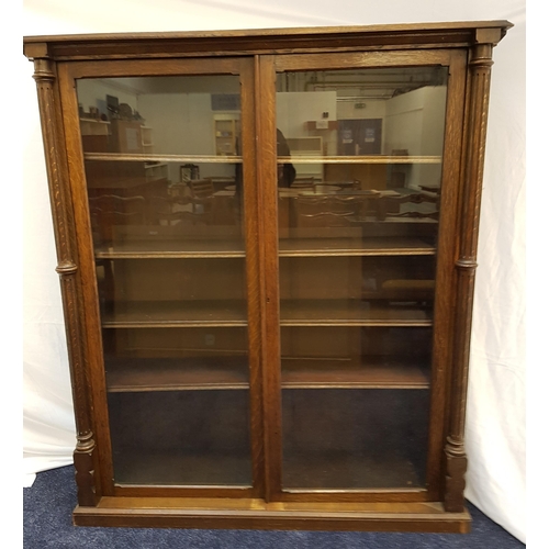 372 - OAK BOOKCASE
with a moulded top above a pair of glass doors flanked by a pair of columns, the interi... 