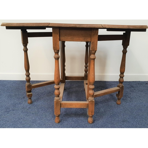 585 - OAK GATELEG DINING TABLE
with shaped drop flaps, standing on turned supports united by a stretcher, ... 