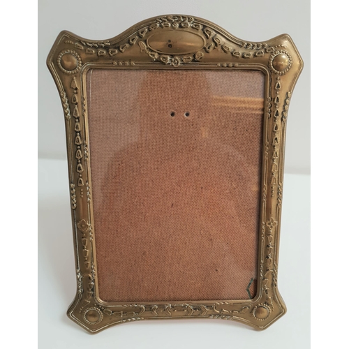 357 - EARLY 20th CENTURY BRASS EMBOSSED PHOTOGRAPH FRAME
decorated with swags of husks, with a fold out re... 