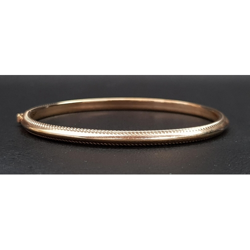 8 - NINE CARAT GOLD BANGLE
with ribbed edge detail and safety clasp, approximately 4.3 grams