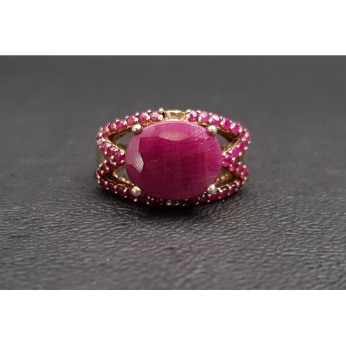 17 - RUBY DRESS RING
the central oval cut ruby surrounded by smaller rubies to the pierced setting, in si... 