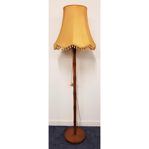 605 - SATINWOOD STANDARD LAMP
raised on a circular base with a simulated bamboo column and a shaped shade,... 