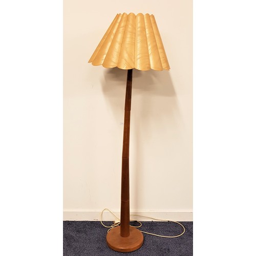 561 - TEAK STANDARD LAMP
raised on a circular base with a tapering column and scalloped shade, 153cm high