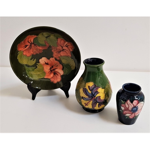 251 - THREE PIECES OF MOORCROFT
comprising an ovoid vase decorated in the hibiscus pattern on a green grou... 