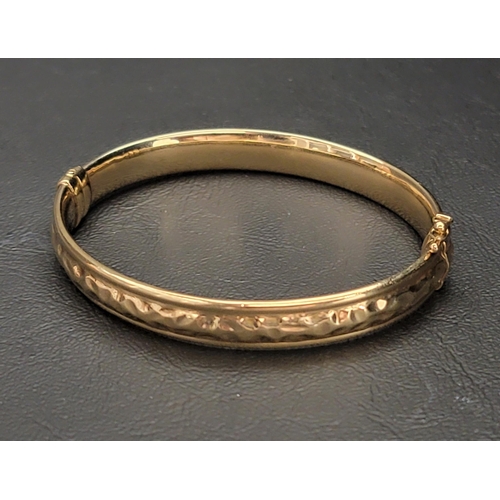 68 - NINE CARAT GOLD HINGED BANGLE 
the bangle with a textured design and a safety clasp, approximately 1... 