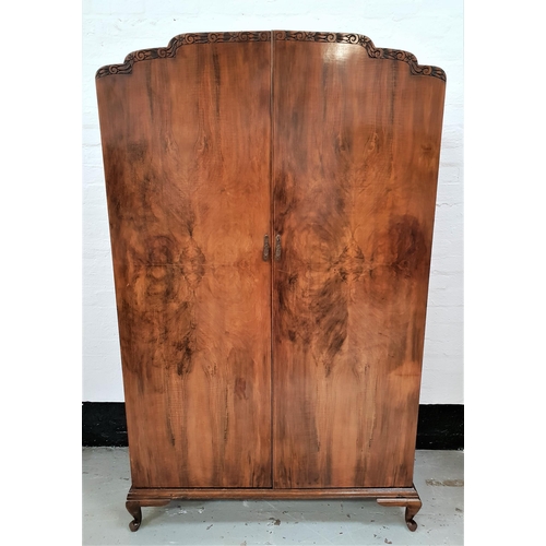 489 - 1950s WALNUT WARDROBE
with a pair of shaped doors opening to reveal an internal mirror, shelf and ha... 