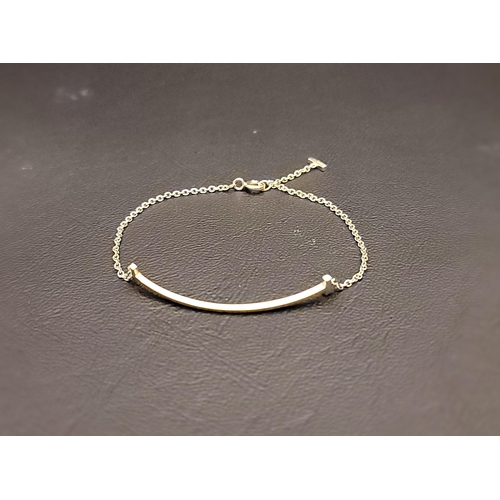 106 - TIFFANY & CO. EIGHTEEN CARAT GOLD SMILE BRACELET
the chain bracelet with a central curved double end... 