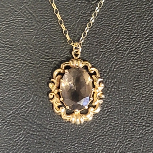 81 - SMOKY QUARTZ PENDANT
the oval cut quartz in nine carat gold pierced scroll decorated mount, on nine ... 