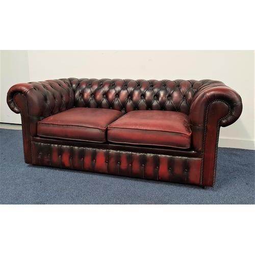 427 - CHESTERFIELD SOFA
with a deep button back and arms with decorative metal stud detail, covered in ox ... 