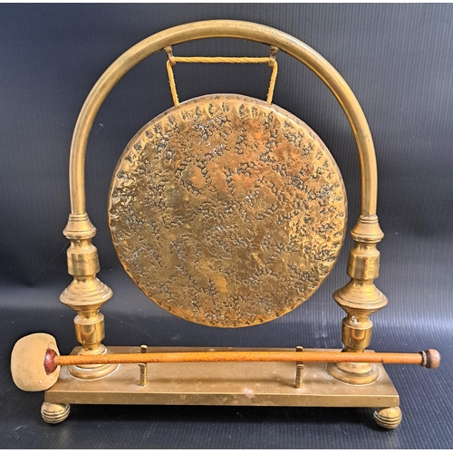 257 - BRASS TABLE GONG
with a rectangular base on ball supports, with an arched suspension arm with a circ... 