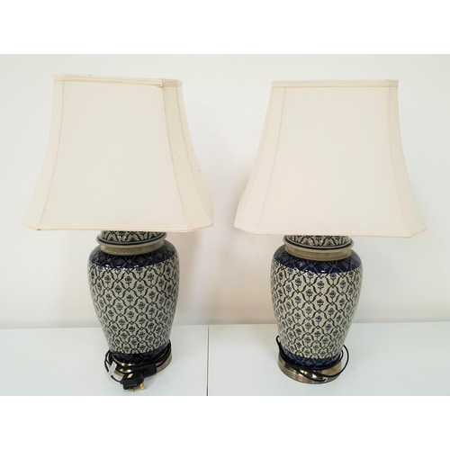 412 - PAIR OF IZNIK STYLE POTTERY TABLE LAMPS
with a blue and cream decorated body with shaped cream fabri... 