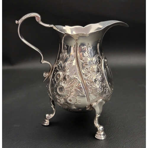 133 - GEORGE II SILVER CREAM JUG
raised on three feet with profuse foliate and scroll embossed decoration,... 