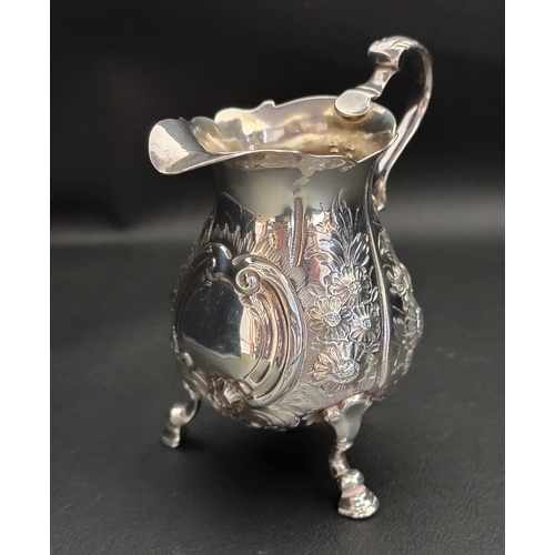 133 - GEORGE II SILVER CREAM JUG
raised on three feet with profuse foliate and scroll embossed decoration,... 