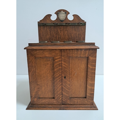 189 - EDWARDIAN OAK SMOKERS CABINET
the shaped raised back with a presentation plaque above a stand for fo... 