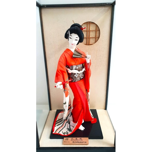 222 - JAPANESE GEISHA DOLL
in traditional dress holding fan, in glazed cabinet and with hand painted woode... 