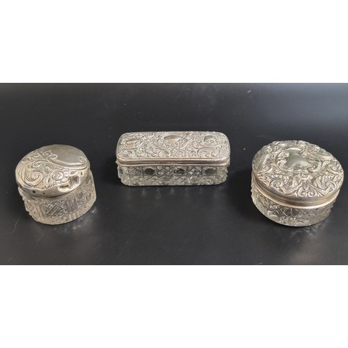 158 - THREE EARLY 20th CENTURN SILVER TOPPED GLASS DRESSING TABLE POTS
all with profuse scroll decoration ... 