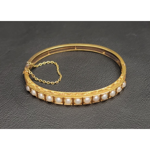 64 - PEARL SET UNMARKED HIGH CARAT GOLD BANGLE
late 19th/early 20th century, the bangle with engraved scr... 