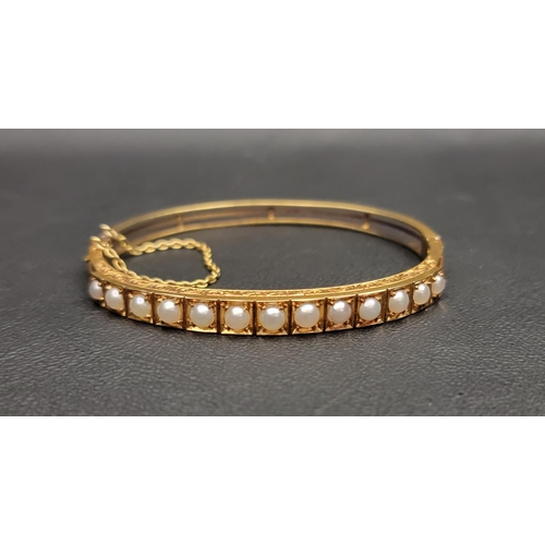 64 - PEARL SET UNMARKED HIGH CARAT GOLD BANGLE
late 19th/early 20th century, the bangle with engraved scr... 