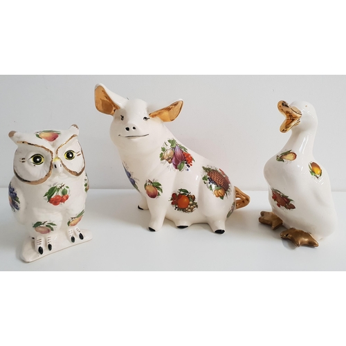 173 - THREE POTTERY ANIMALS
decorated with orchard fruit, comprising a duck, 21.5cm high, a seated pig, 24... 