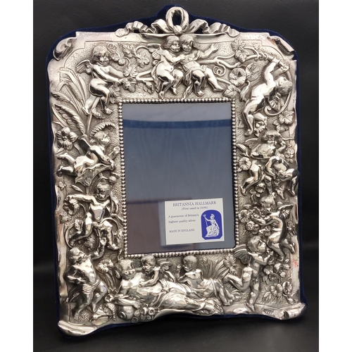 125 - ELIZABETH II BRITANNIA SILVER PHOTOGRAPH FRAME
decorated with putti in relief, London 1997 by Neil L...