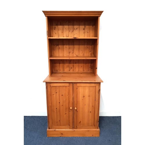 WAXED PINE DRESSER
the upper section with open shelves, the base with a pair of panelled cupboard doors, standing on a plinth base, 185.5cm x 84.5cm x 56cm