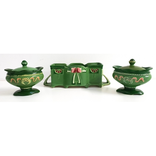 PAIR OF EICHWALD OVAL POTTERY DISHES
with a green ground and oval lids, raised on a shaped pedestal base with swag and wreath decoration, the bases impressed 2504, 10cm high, and an Eichwald shaped rectangular flower trough decorated with stylised flowers and shaped handles, the base impressed 7551, 23.5cm wide (3)