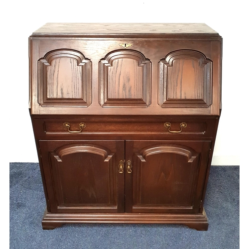 OAK BUREAU
with a carved panel fall flap opening to reveal a fitted interior above a long drawer with a pair of carved panel doors below, standing on bracket feet, 109cm x 90cm x 47cm