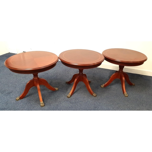 THREE MAHOGANY AND CROSSBANDED OCCASIONAL TABLES
with circular tops on a turned columns with four outswept supports with brass lion paw feet, 53.5cm high (3)