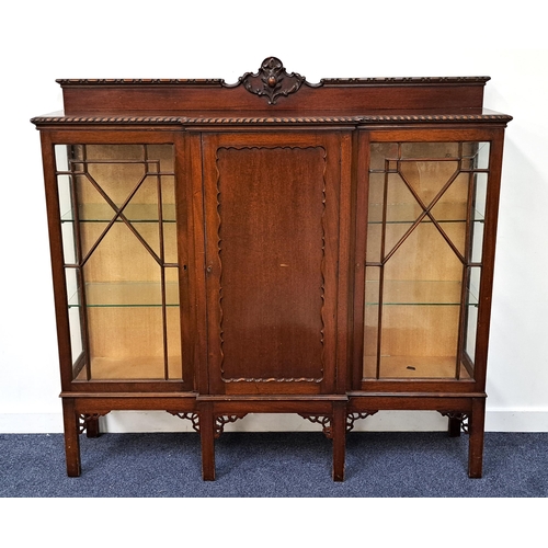 MAHOGANY BREAKFRONT DISPLAY CABINET
with a carved and shaped raised mirror back above a central panelled door flanked by a pair of glass panelled doors opening to reveal glass shelves, standing on plain supports, 145cm x 152cm