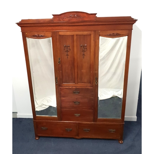 EDWARDIAN MAHOGANY PRINCESS WARDROBE
with an arched and moulded cornice above a central cupboard door with moulded decoration above three drawers, flanked by a pair of bevelled mirror doors opening to reveal hanging rails, the base with two deep long drawers, standing on front stout bun feet, 218cm x 162cm x 52.5cm