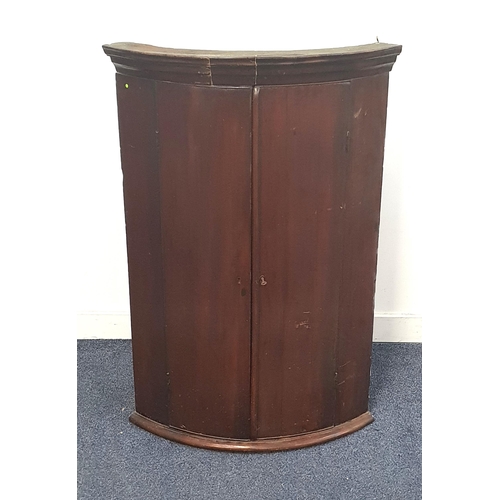 GEORGE III MAHOGANY BOW FRONT CORNER CUPBOARD
with a pair of doors opening to reveal a shelved interior, 99.5cm high