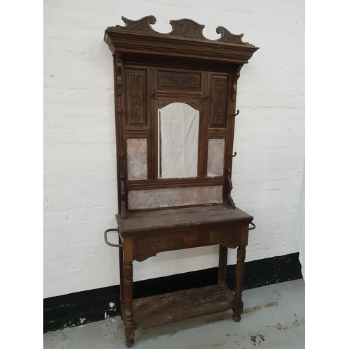 EDWARDIAN OAK HALL STAND
with a shaped carved top rail above carved panels with a central arched bevelled mirror and marble panels, with an arrangement of six hat hooks above a shelf with a frieze drawer, standing on turned supports united by an undertier, 211cm x 123cm