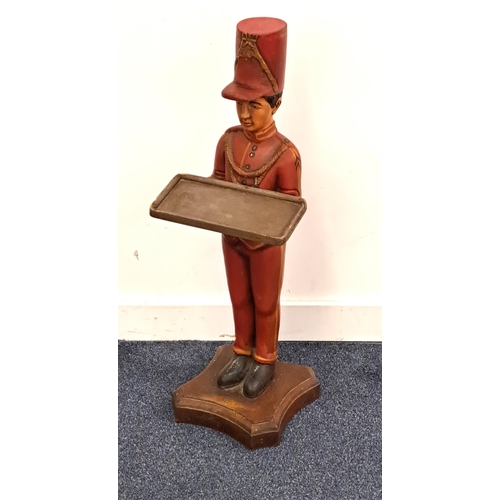 CARVED FIGURAL DUMB WAITER
in the form of a soldier, with his hands outstretched holding a rectangular tray, raised on a shaped base, 77.5cm high