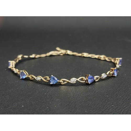 TANZANITE AND DIAMOND SET BRACELET
the six trillion cut tanzanites separated by diamond set entwined links, in nine carat gold, 19.3cm long and approximately 4.5 grams
