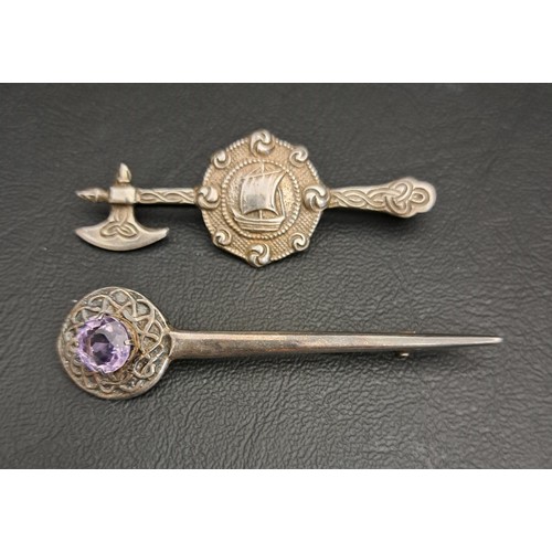 TWO CELTIC SILVER BROOCHES
one in the form of an Axe and galleon decorated shield, with entwined Celtic decoration, and the other with amethyst set finial within an entwined border