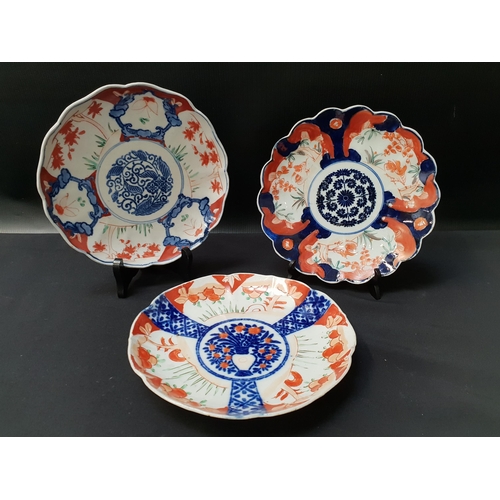 221 - THREE JAPANESE IMARI BOWLS
each with a wavy rim and decorated in iron red and blue, each 21cm diamet... 