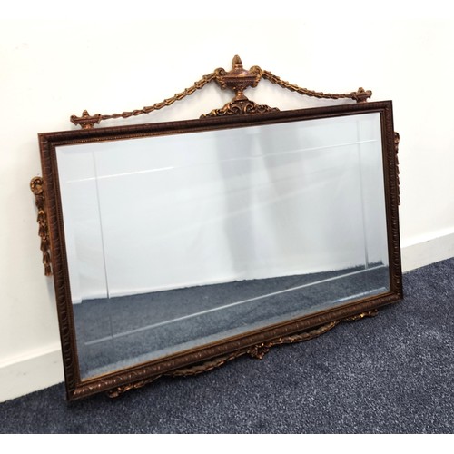 387 - RECTANGULAR WALL MIRROR
with a textured wood frame surmounted with an urn and garlands, with a bevel... 