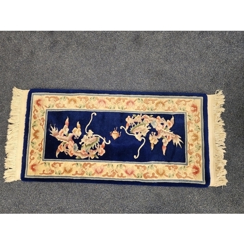 407 - CHINESE WASH RUG
with a navy blue ground decorated with dragons, in a floral border, fringed, 130cm ... 