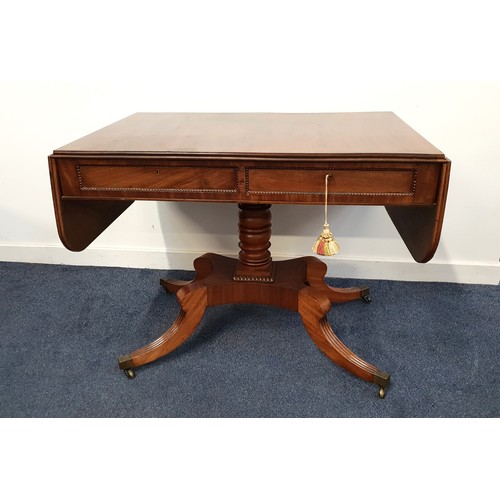 REGENCY ROSEWOOD AND CROSSBANDED SOFA TABLE
with shaped drop flaps above two opposing and dummy drawers, standing on a turned column and quadruple splayed legs with brass caps and casters, 72.5cm x 151cm x 63.5cm
