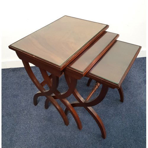 382 - NEST OF WALNUT OCCASIONAL TABLES
with rectangular inset glass tops, standing on crossover supports, ... 