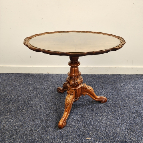 WALNUT OCCASIONAL TABLE
with a circular pie crust top, standing on a turned column and tripod base, 53cm high
