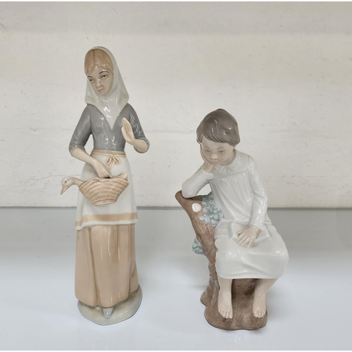 LLADRO FIGURINE OF A YOUNG BOY IN NIGHTDRESS
seated on a tree stump, 21cm high; together with a Miquel Requena figure of a woman holding a duck in a basket, 26.5cm high (2)