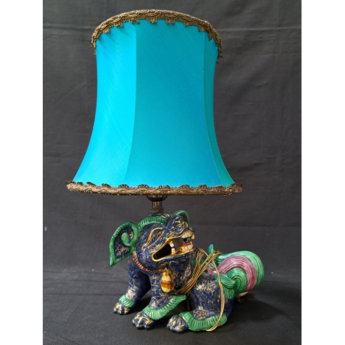 CHINESE STYLE POTTERY FOO DOG TABLE LAMP
the blue body with gilt highlights and a green and mauve tail, with a shaped turquoise shade, 44cm high